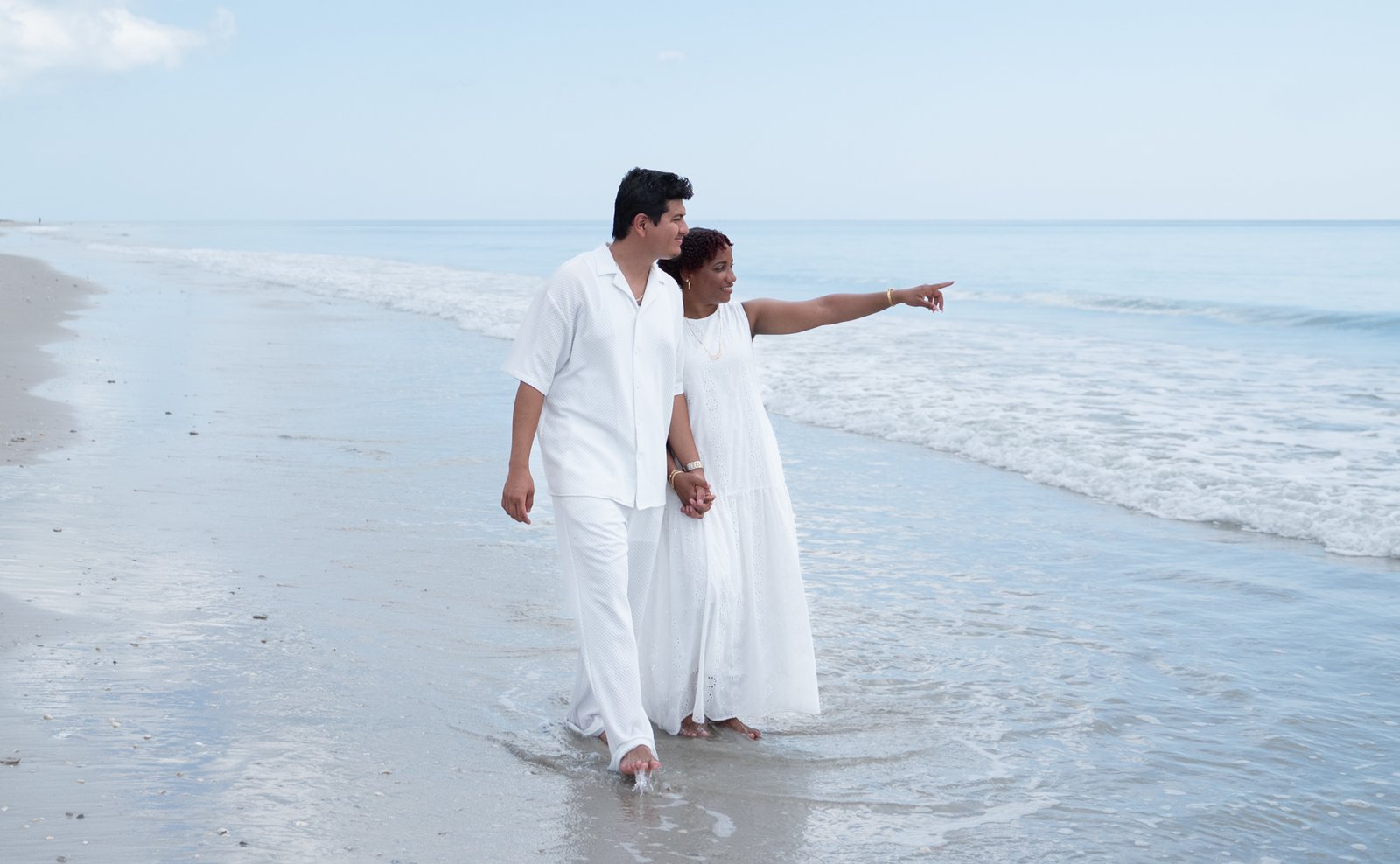 Yassiel pointing toward the horizon as they walk the beach